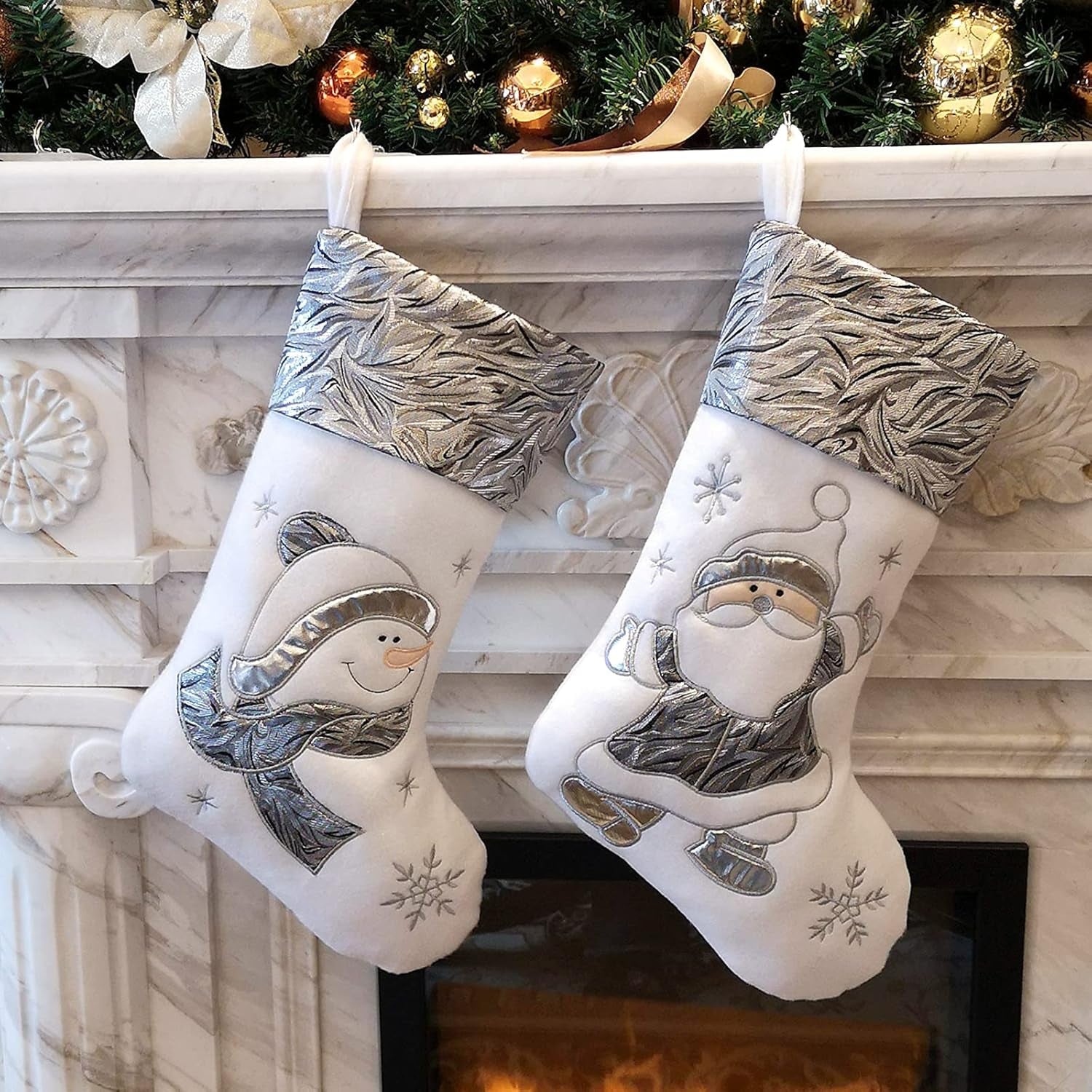 Two Christmas stockings with snowman and Santa designs hanging on a fireplace mantle.