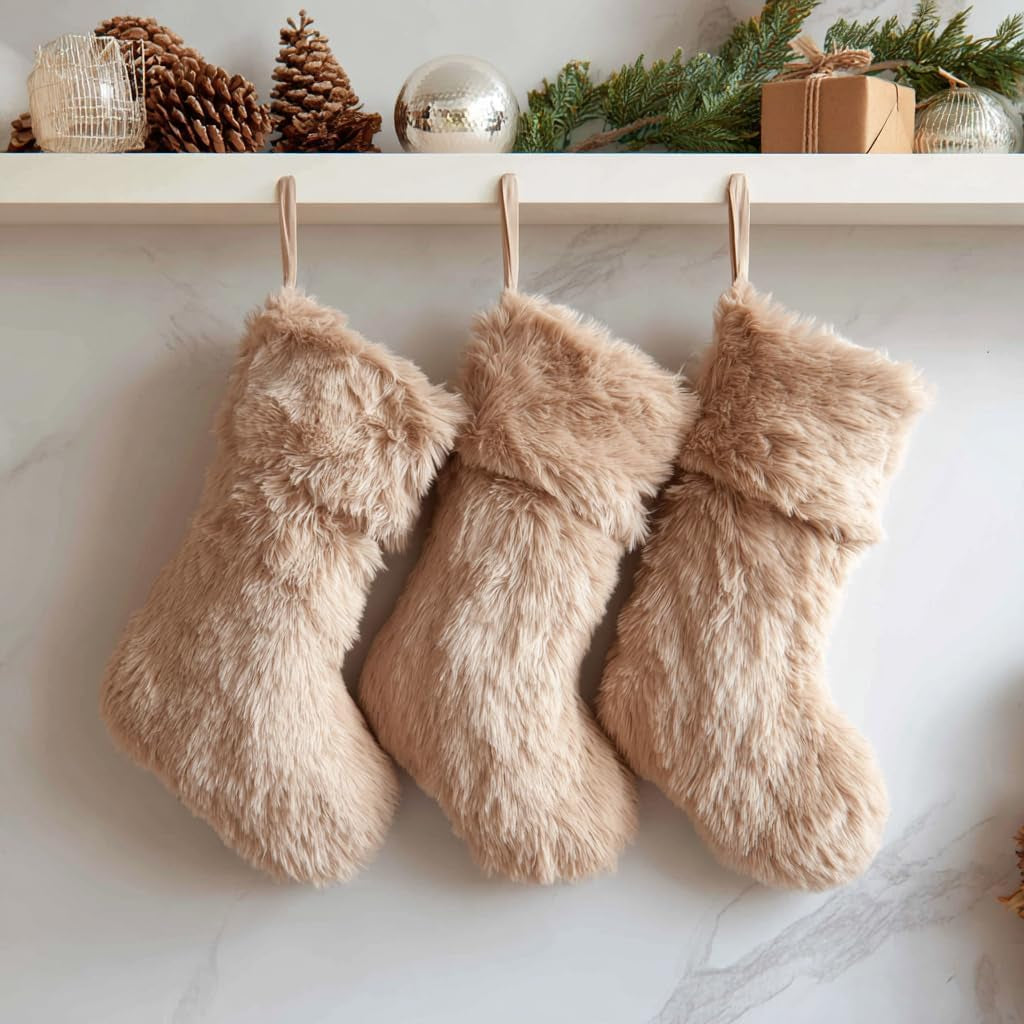 Three fluffy beige stockings hanging on a white wall with decorative items above.
