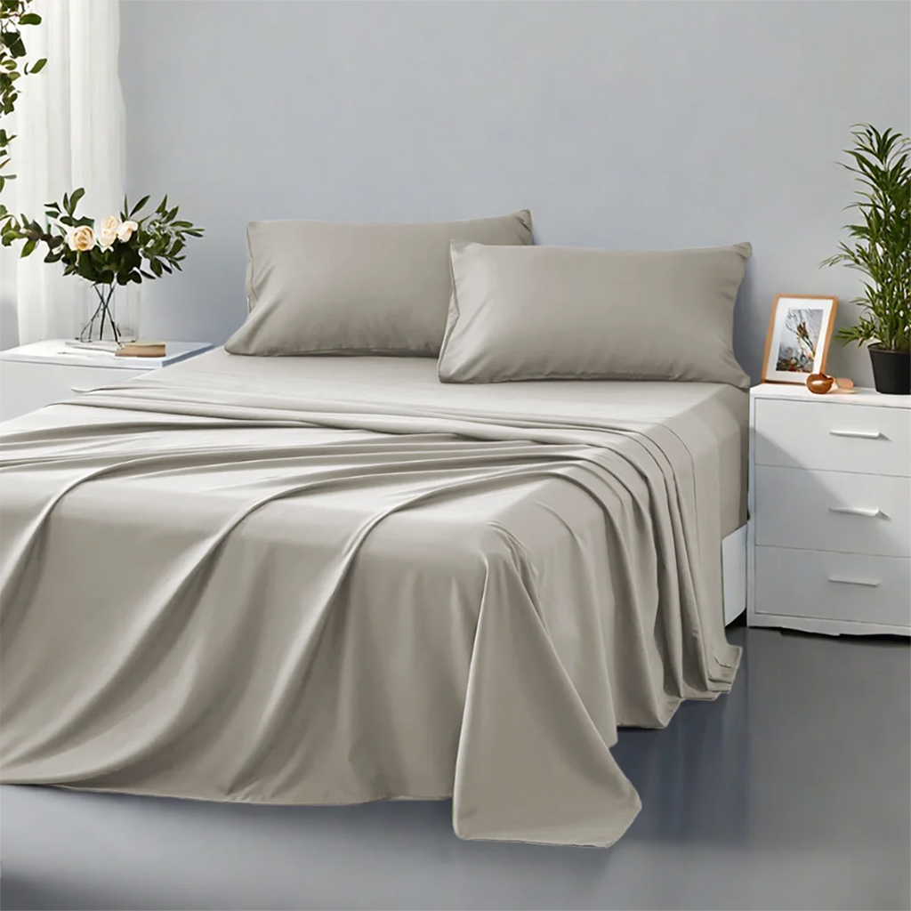 Beige bed sheets and pillows on a bed in a bedroom setting with plants and decor.