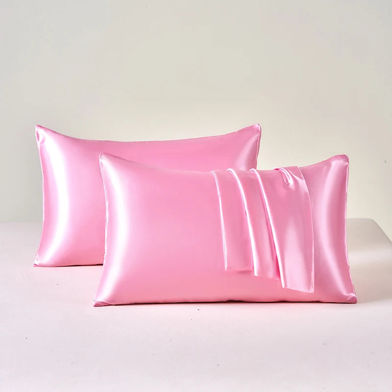 Two pink satin pillowcases on a light gray background