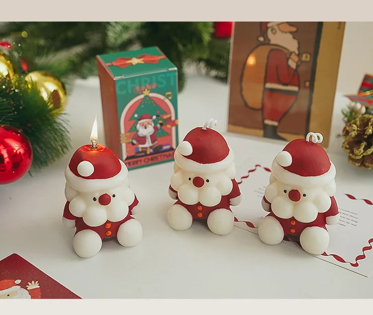 Three Santa Claus-shaped candles on a table with Christmas decorations 