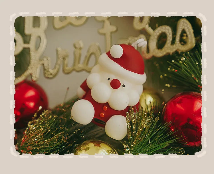 Decorative Christmas ornament with a Santa Claus figure surrounded by greenery and red ornaments.
