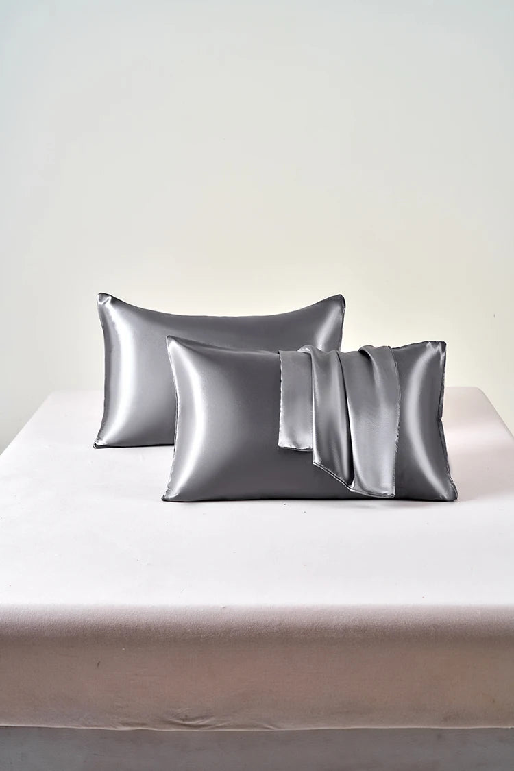 Two silver satin pillows on a white bed