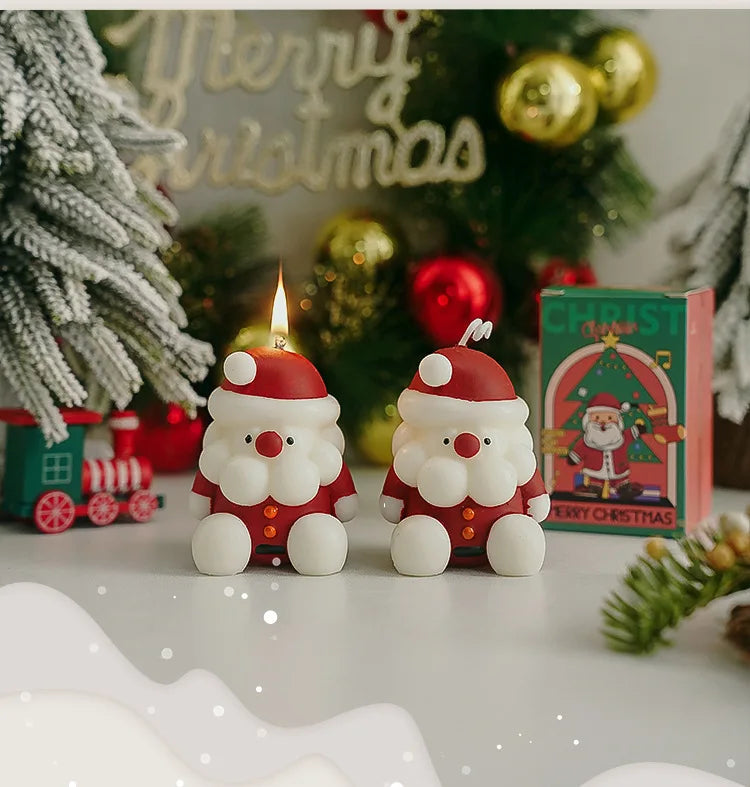 Two Santa Claus-shaped candles on a Christmas-themed background with 'Merry Christmas' decorations.